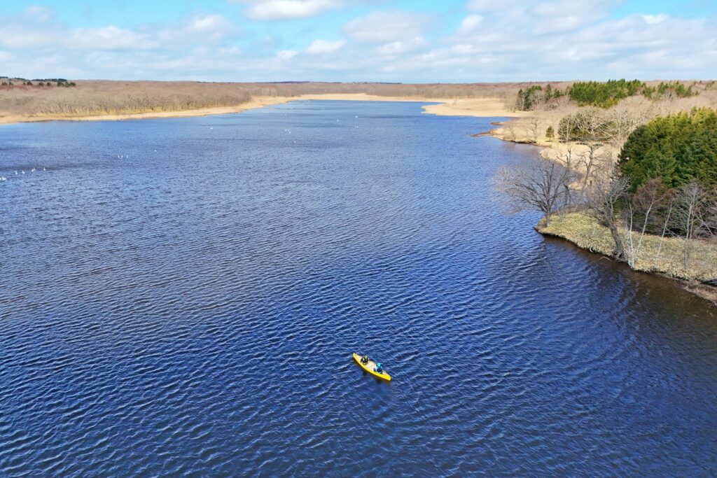 北海道別海町の神秘的な湖（ぱらさんと沼）をカヌーで漕ぐ様子。流れの無い静かな水面と緑の自然