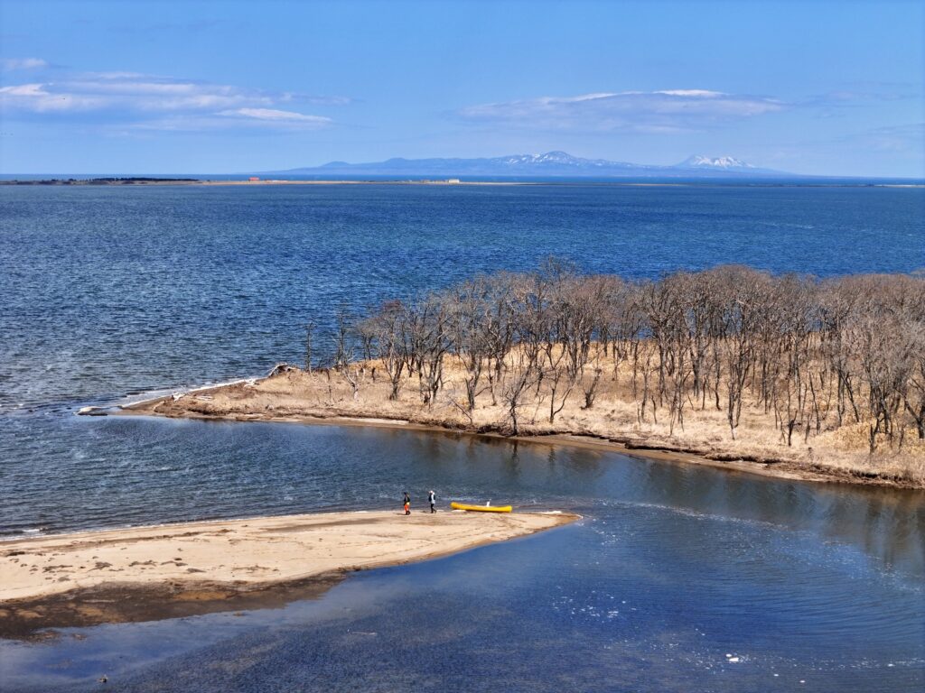 北海道別海町・野付湾にそそぐ飛仁帯川の河口をカヌーで進む様子。野付半島と国後島を望む雄大な景色